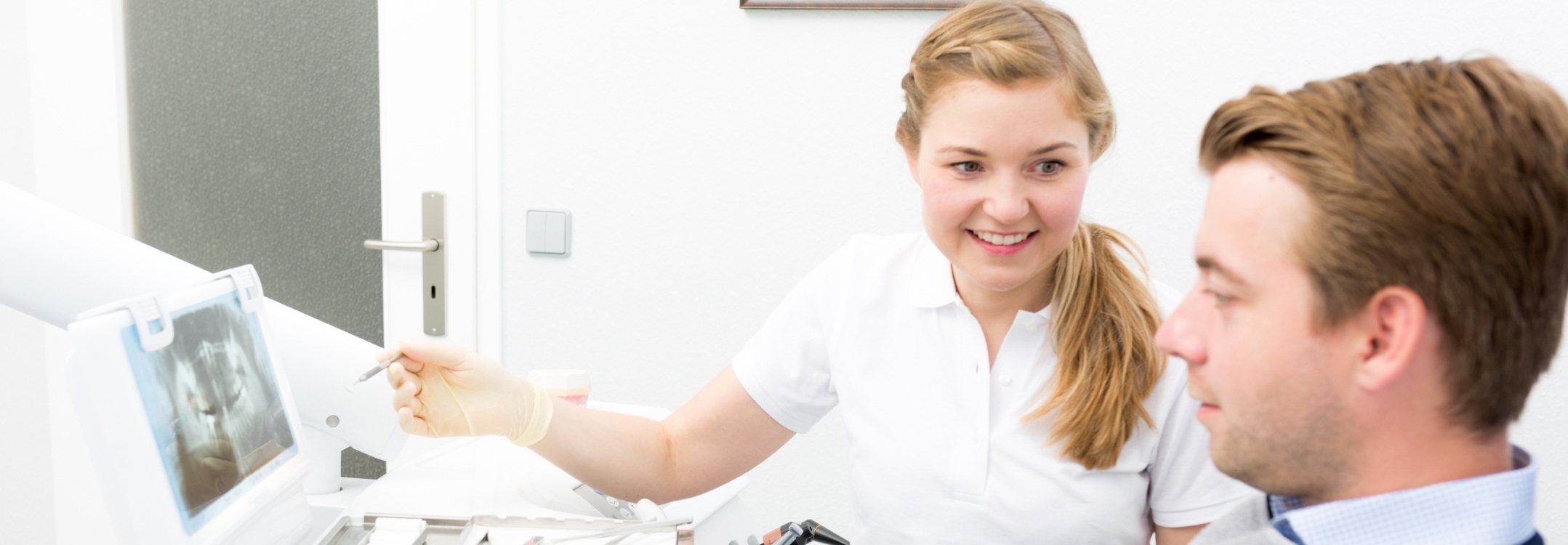 Intro Photo: Zahnärztin der Zahnarztpraxis Stralsund Dr. Stefanie Motz erklärt einem Patienten am Behandlungsstuhl eine digitale Röntgenaufnahme am Monitor.