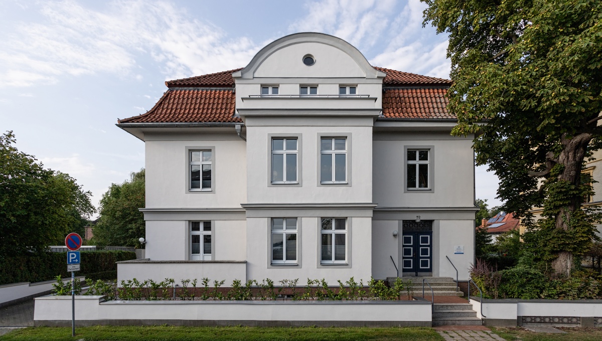 Gründerzeitliches, elegant renoviertes Praxisgebäude der Zahnarztpraxis DIE ZAHNARZTPRAXIS in Stralsund mit weißer Fassade, roten Ziegeldächern und modernem Eingangsbereich.