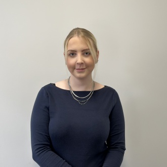 Porträt von ZFA Sonja Werk aus DIE ZAHNARZTPRAXIS Stralsund, im dunkelblauen Oberteil vor hellem Hintergrund, zuständig für Praxisorganisation und Verwaltungsassistenz nach Zusatzausbildung.