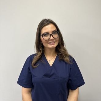 Porträt von Zahnärztin Louisa Hofmann aus DIE ZAHNARZTPRAXIS Stralsund, im dunkelblauen Kasack vor hellem Hintergrund, mit Erfahrung in Implantatprothetik, CEREC und moderner Seitenzahnrestauration.